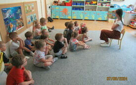 Bibliotekarka czyta dzieciom siedzącym na podłodze w przedszkolu