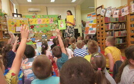 Bibliotekarka prowadzi zajęcia dla dzieci, kt&oacute;re w grupie siedzą na podłodze.