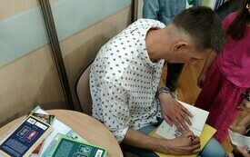 Pisarz składa autograf na swojej książce