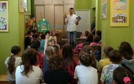 Pisarz pokazuje dzieciom swoje książki na spotkaniu w bibliotece