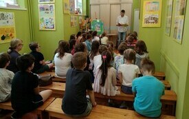 Grupa dzieci siedzi i słucha pisarza na spotkaniu autorskim