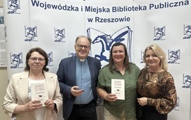 Ksiądz Kazimierz Sowa pozuje do zdjęcia z prowadzącą spotkanie i z bibliotekarkami 