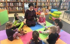 Bibliotekarka siedzi z dziećmi w kręgu