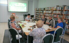 Przy stole siedzą czytelniczki i bibliotekarka, rozmawiają.
