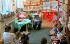 Bibliotekarka z książką podczas czytania dzieciom. 