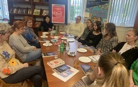 Grupa ludzi siedzi i rozmawia o książkach. Biblioteka.