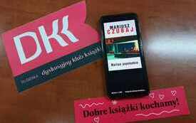 Na stoliku telefon i logo DKK