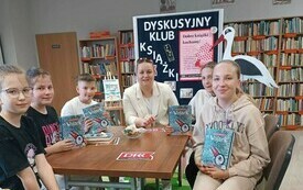 Kilka dzieci siedzi na spotkaniu wokół stołu