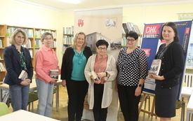 Grupa kobiet stoi obok siebie, jedna z nich trzyma książkę &quot;Jedyne wyjście&quot; R. Ćwirleja 