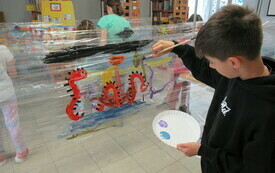 Chłopiec maluje koniki morskie na folii. 