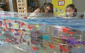Bibliotekarka i dziewczynka tworzą rysunki rybek na folii.