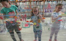 Dziewczynki malują na folii kolorowe obrazki. 