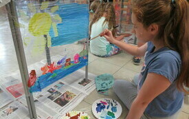 Dziewczynka maluje pejzaż na folii. 