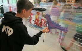 Chłopiec maluje smoka na folii.