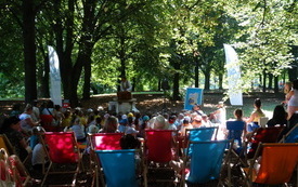 W parku pod drzewami zgromadzona liczna publiczność na teatrzyku dla dzieci.