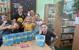 Grupa dzieci stoi obok siebie, na stole książki Justyny Bednarek.