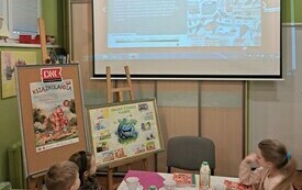 Dwie dziewczynki i chłopiec siedzą przy stole i rozmawiają.
