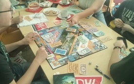 Młodzi ludzie grają w grę planszową monopoly.
