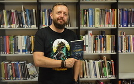 Michał Śmielak, pisarz kryminałów trzyma w rękach książkę.