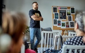 Kilka krzeseł, na środku stoi Michał Śmielak, autor książek.