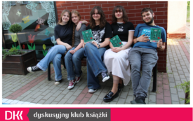 Grupa młodych ludzi siedzi na ławce i trzyma książki w rękach.