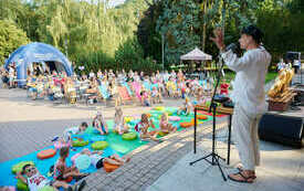 Na scenie mężczyzna w białym stroju i kapeluszu. Przed nim zgromadzona publiczność.