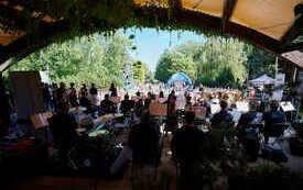 Na scenie orkiestra z chórem, przed sceną zgromadzona publicznośc