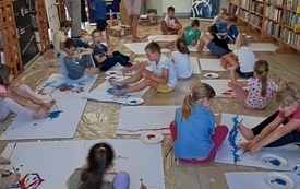 Grupa dzieci maluje ośmiorcę używając dłoni i stóp jako pędzli