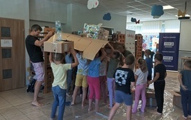 Grupa dzieci buduje tratwę z kartonów