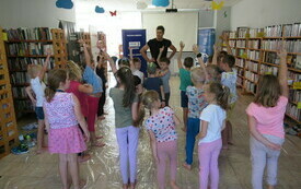 Grupa dzieci stoi w rękami w górze