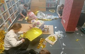 Dzieci i mamy podczas wykonywania zbroi z piór, foli termicznych.