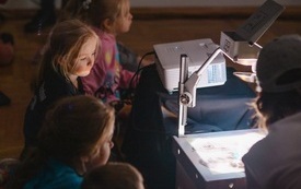 Dzieci patrzą na pracę aktora na multimedialnym rzutniku.