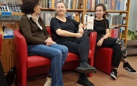 Trzy kobiety siedzące na czerwonych fotelach.