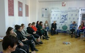 Grupa kobiet w różnym wieku siedzi w sali