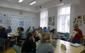 Widok sali szkoleniowej wypełnionej siedzącymi przy stolikach kobietami