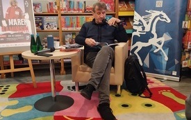 Mężczyzna siedzący na fotelu i czytający książkę.