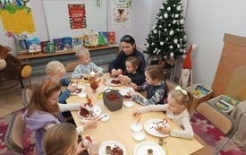 Choinka w kącie. Przy stole mali uczestnicy warsztat&oacute;w plastycznych.