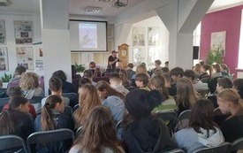 Autor Robert Maciąg trzyma mikrofon i mówi do młodzieży.
