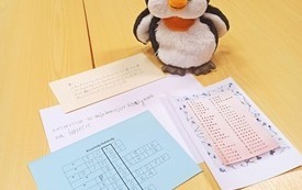 Maskotka pingwinek oraz karty zadań.