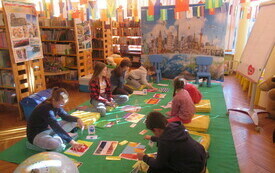 Dzieci na dywanie rozwiązują ćwiczenia dotyczące flag narodowych.