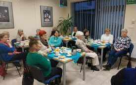 Grupa os&oacute;b siedzi przy stolikach w bibliotece
