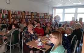 Kobiety zgromadzone w bibliotece na spotkaniu o tematyce urodowej.
