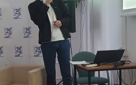 Mężczyzna w okularach z mikrofonem w ręku podczas przemawiania. 