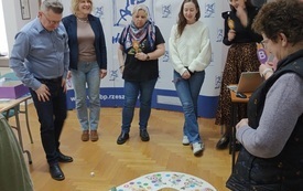 Na podłodze gra. Wok&oacute;ł niej osoby grające.