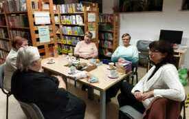 Grupa pięciu os&oacute;b siedzących przy stole w bibliotece