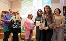 Grupa kobiet z książkami pozuje do zdjęcia.