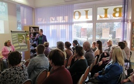 Bibliotekarka wita zebranych na spotkaniu autorskim.