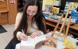 Dziewczyna podpisuje swoją książkę.