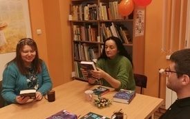 Dwie kobiety i mężczyzna siedzący przy stole z książkami