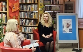 Dwie kobiety siedzą w fotelach. W tle regały z książkami.